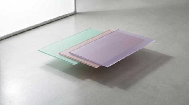 Trois rectangles semi-transparents pastel se chevauchant sur surface béton