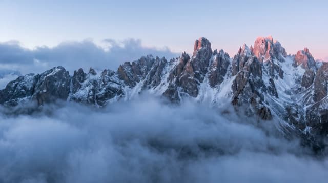 Crête de montagne déchiquetée au-dessus de nuages bas à l'aube, sans aucune construction humaine