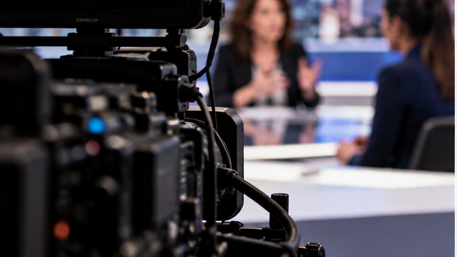 Caméra de télévision au premier plan, un échange flou sur un plateau d'information en arrière-plan