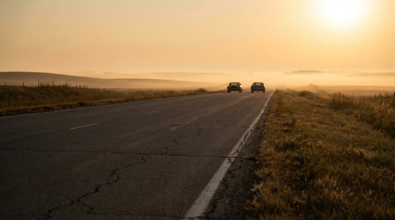 Route de campagne au crépuscule avec deux voitures côte à côte au loin, métaphore visuelle du covoiturage international