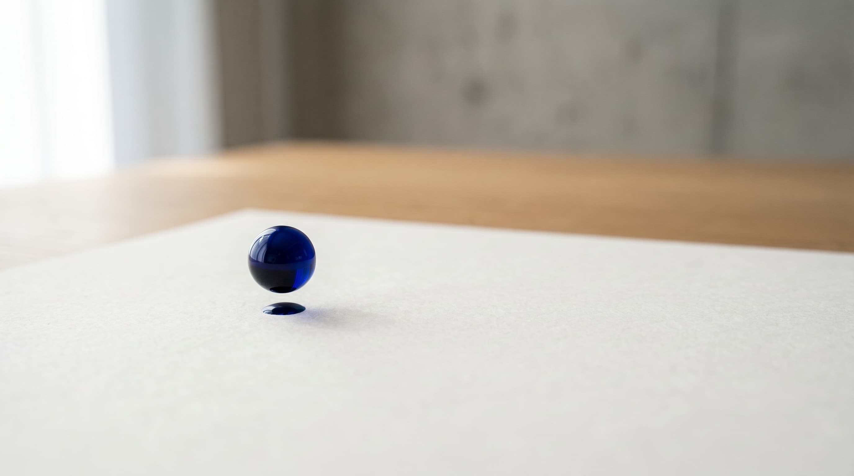 Goutte d'encre bleue suspendue au-dessus d'une feuille blanche, métaphore visuelle du refresh discipliné Doctolib