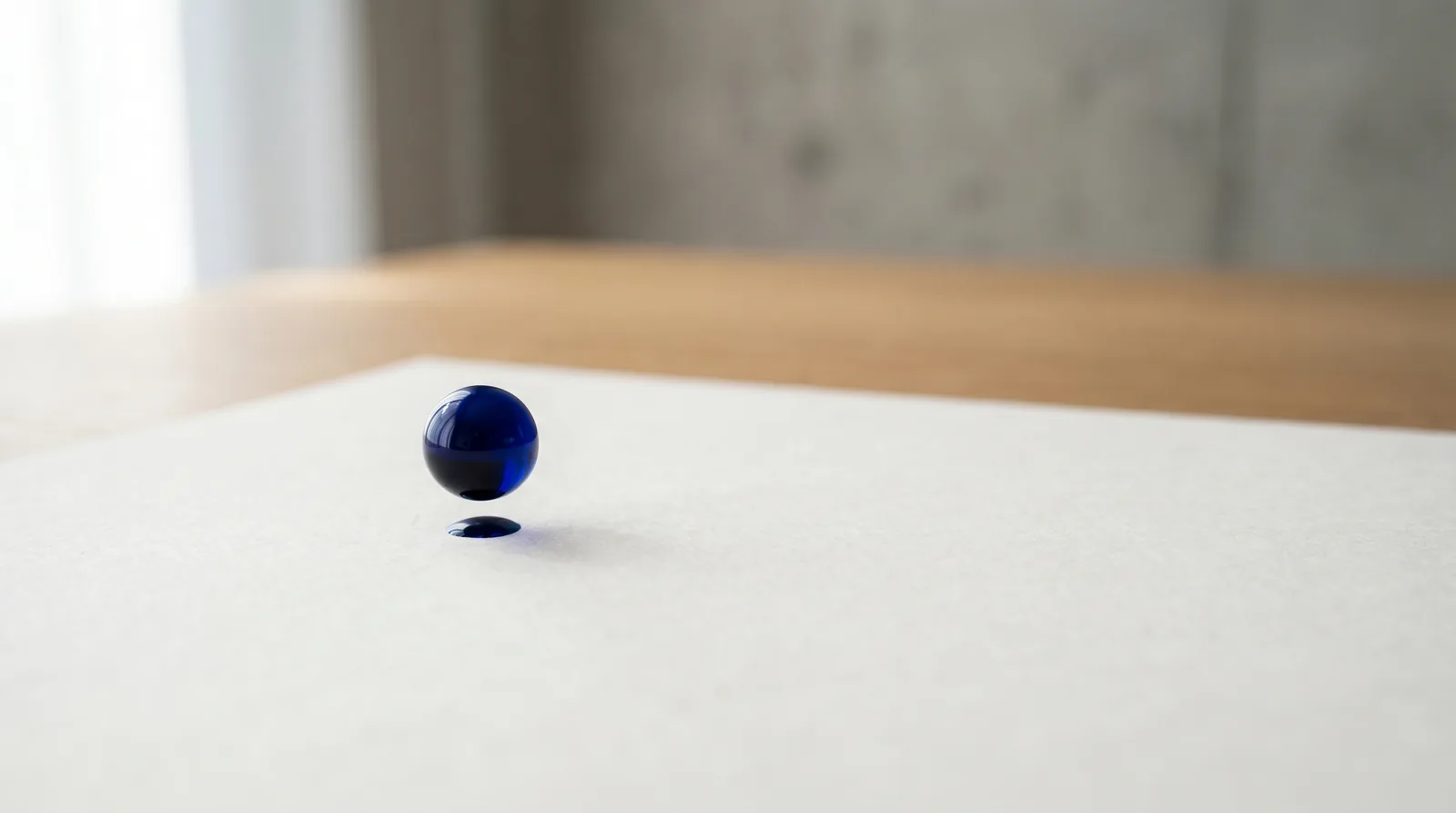 Goutte d'encre bleue suspendue au-dessus d'une feuille blanche