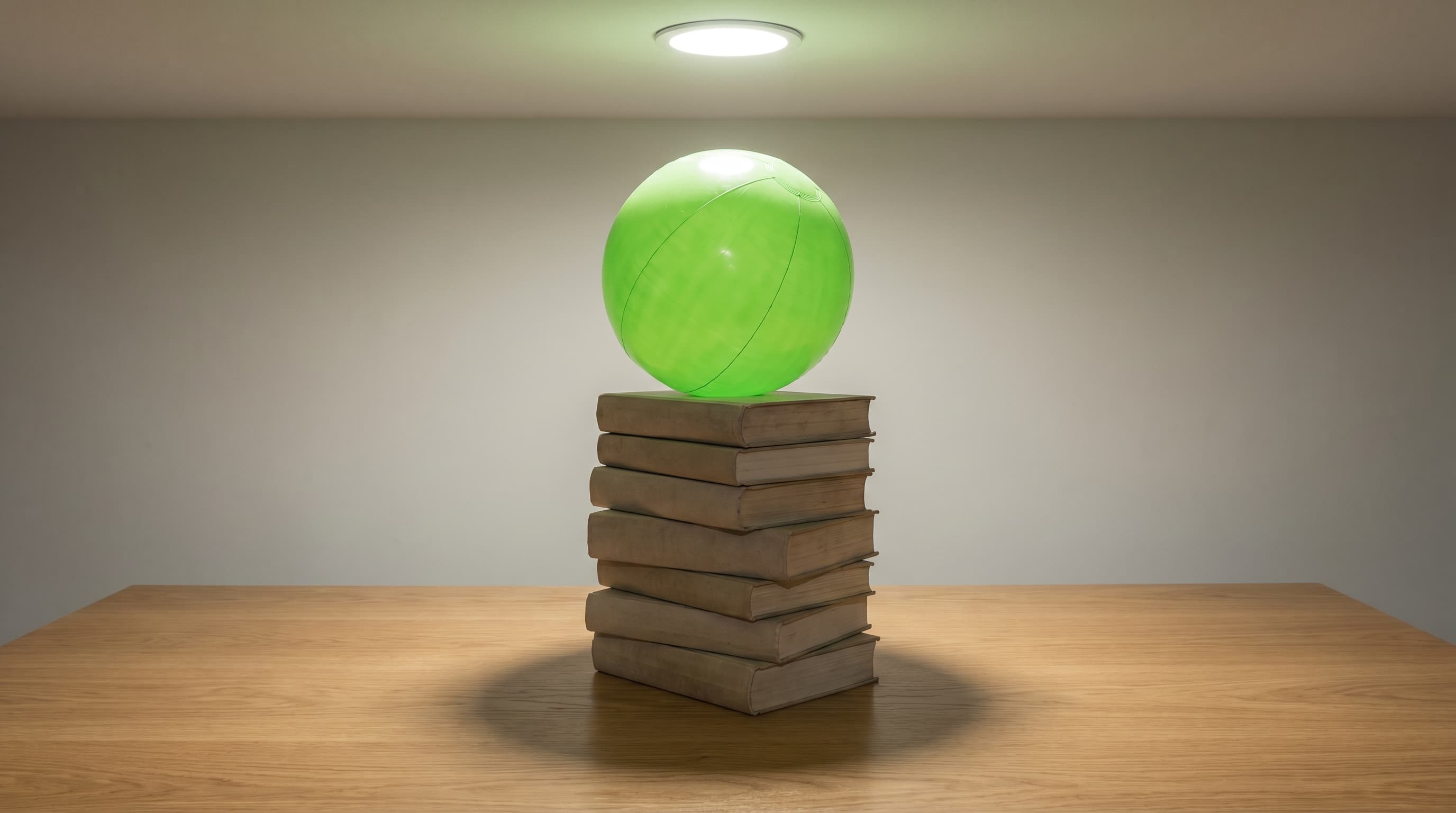 Ballon vert vif en équilibre sur une pile de gros livres reliés, métaphore visuelle de la mascotte qui porte l'apprentissage