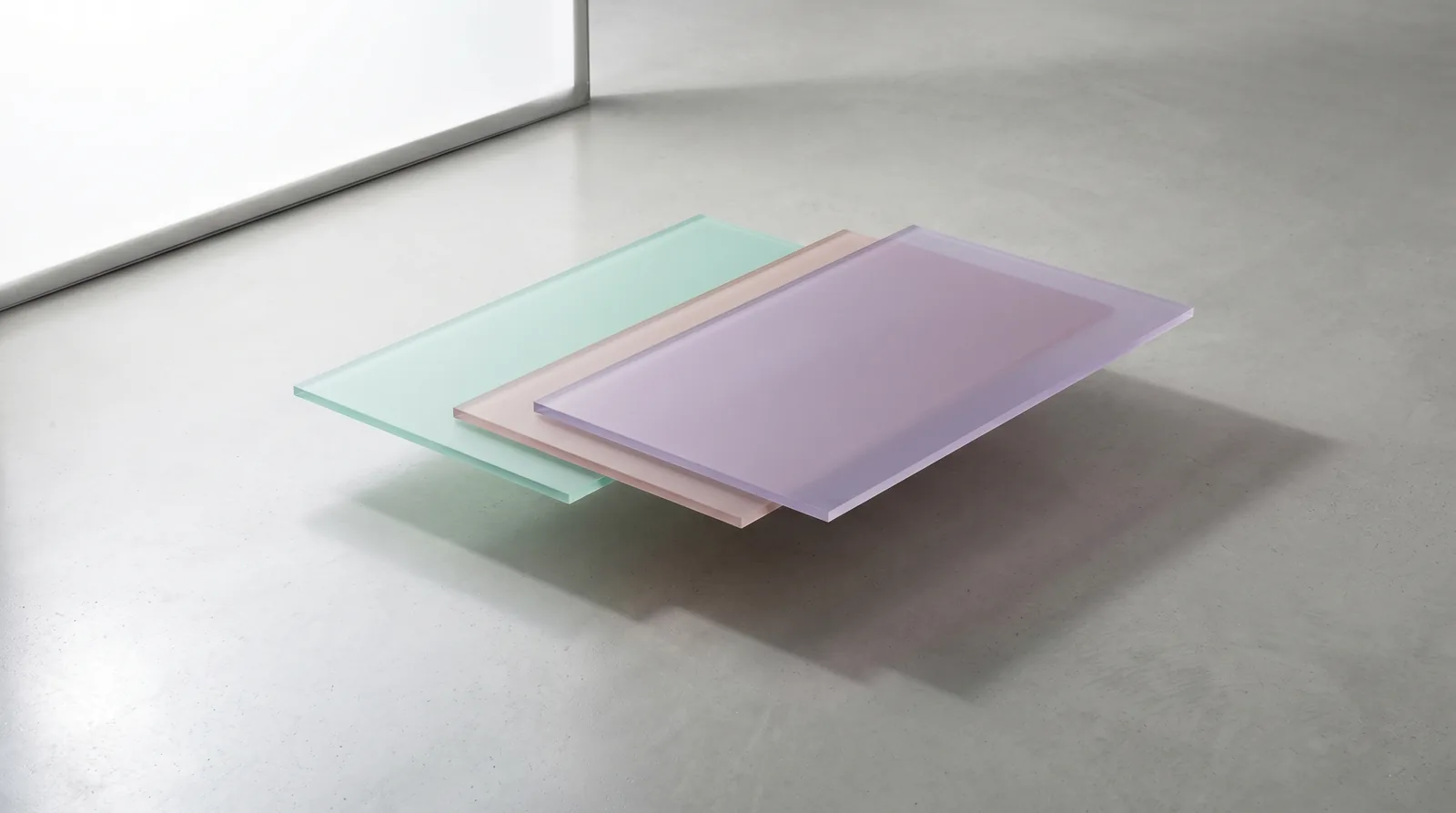 Trois rectangles semi-transparents pastel se chevauchant sur surface béton, métaphore visuelle de l'outil de design collaboratif comme empilement de calques