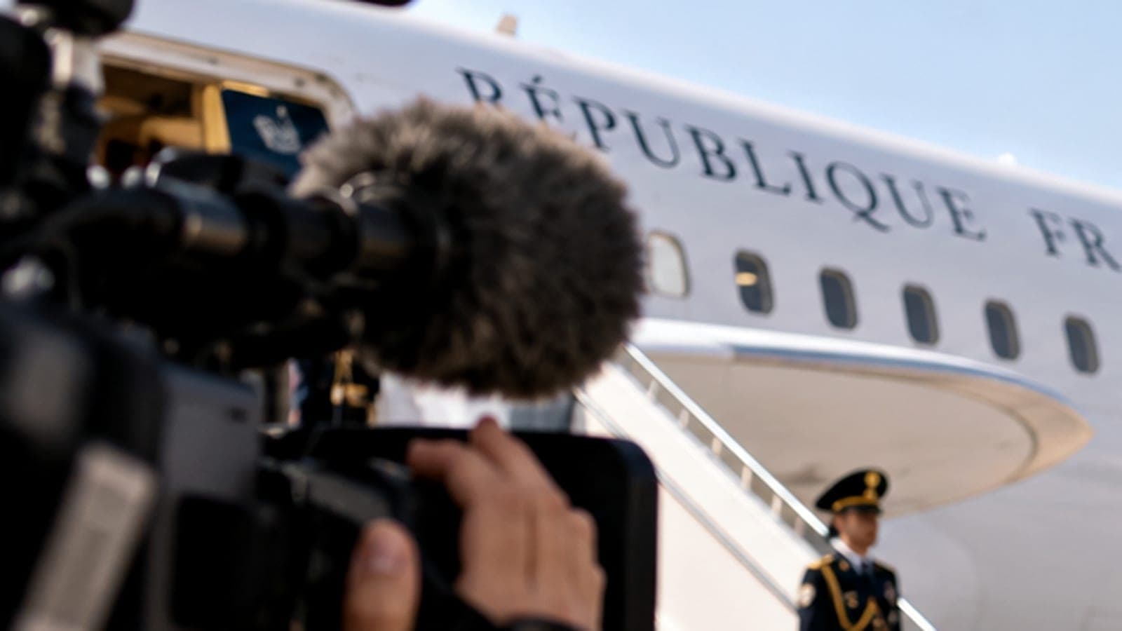 Caméra de télévision devant un avion présidentiel portant l'inscription République française, garde en uniforme au pied de la passerelle